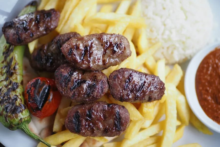 Közlenmiş biber ve patates kızartmasıyla servis edilen ızgara kebapche